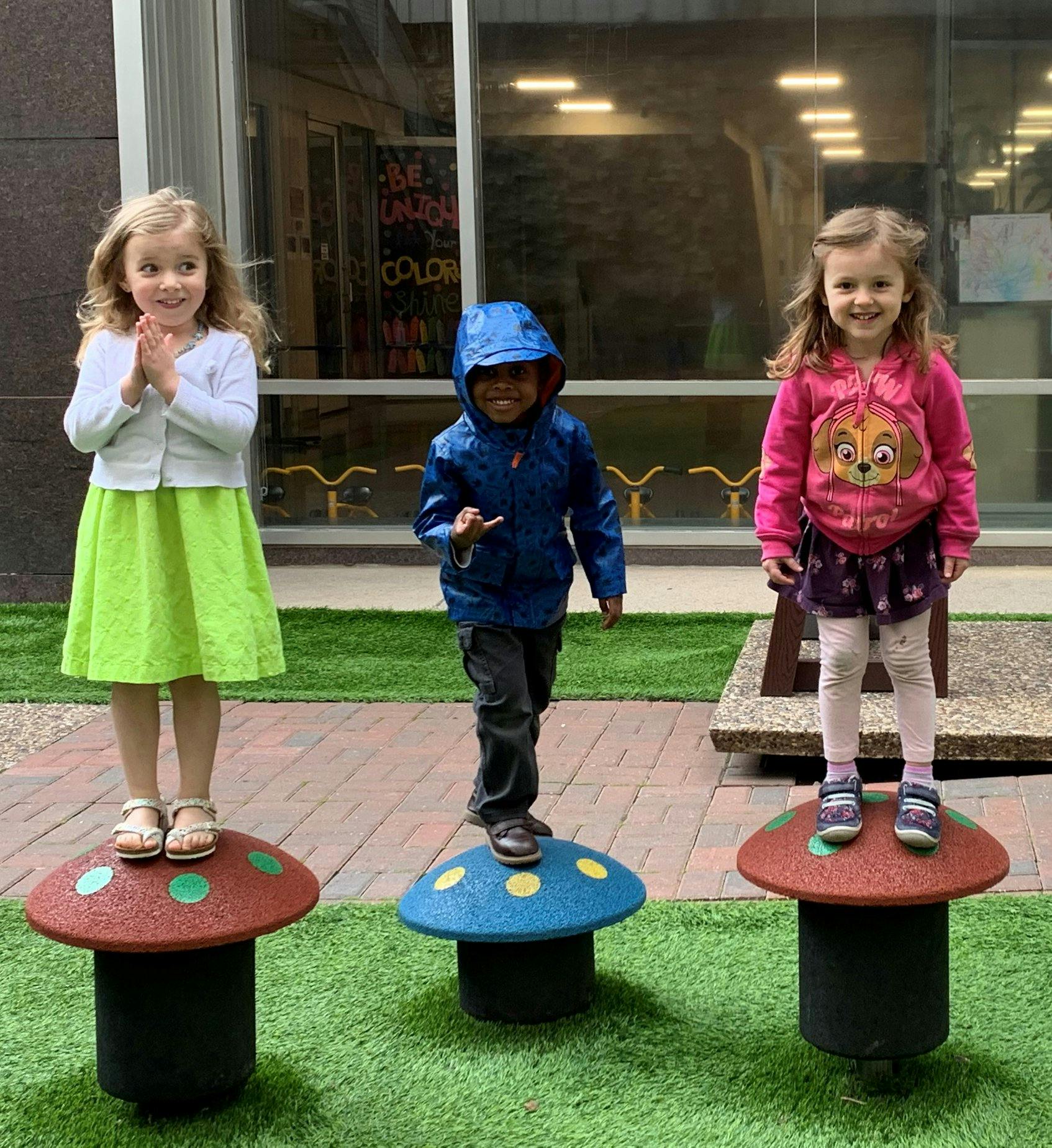 Three children standing on mushroom-shaped play structures