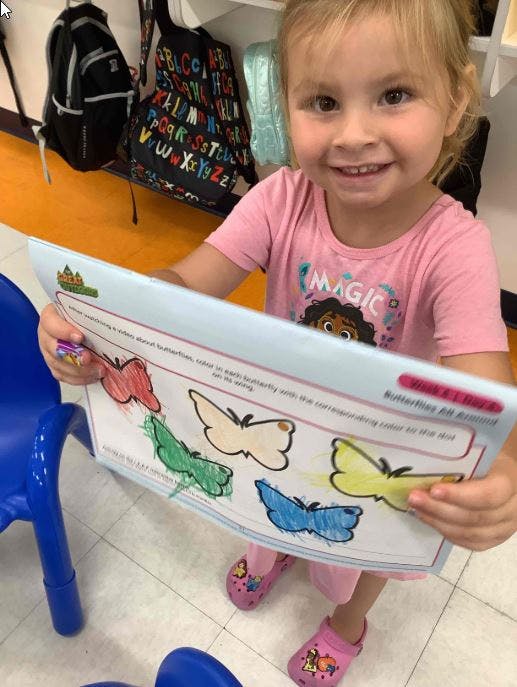 Child holding up a paper with butterfly drawings