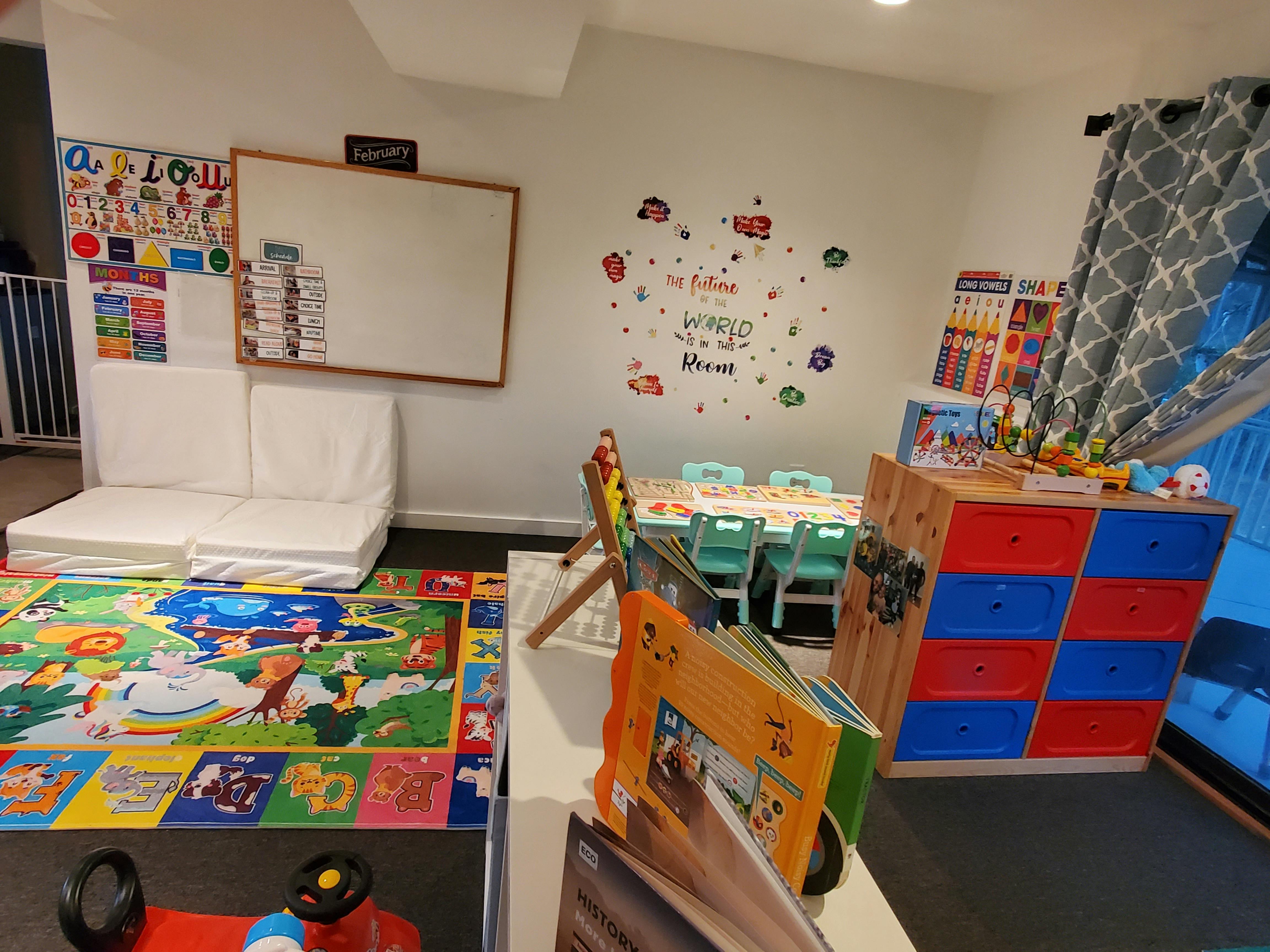 Playroom with colorful rug, whiteboard, small table and chairs, and storage unit