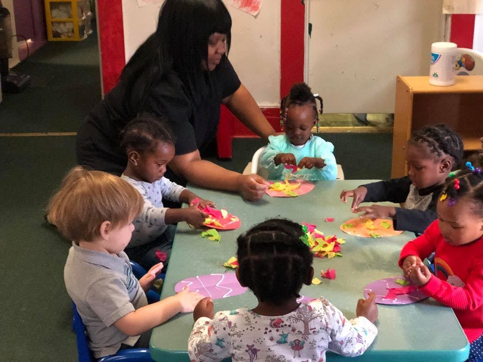 Adult and children sitting at a table doing crafts