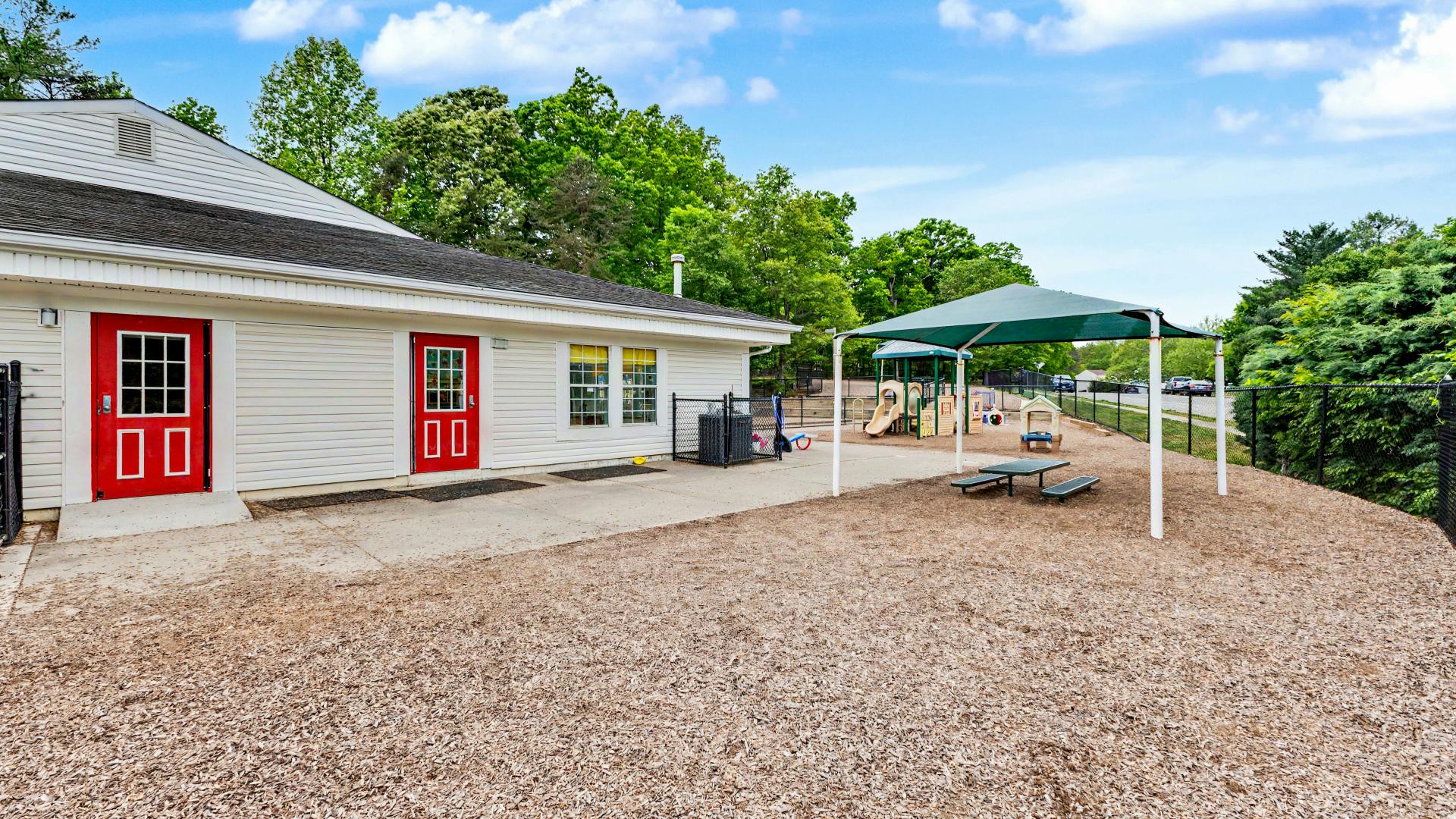 White building with red doors and an outdoor playground area