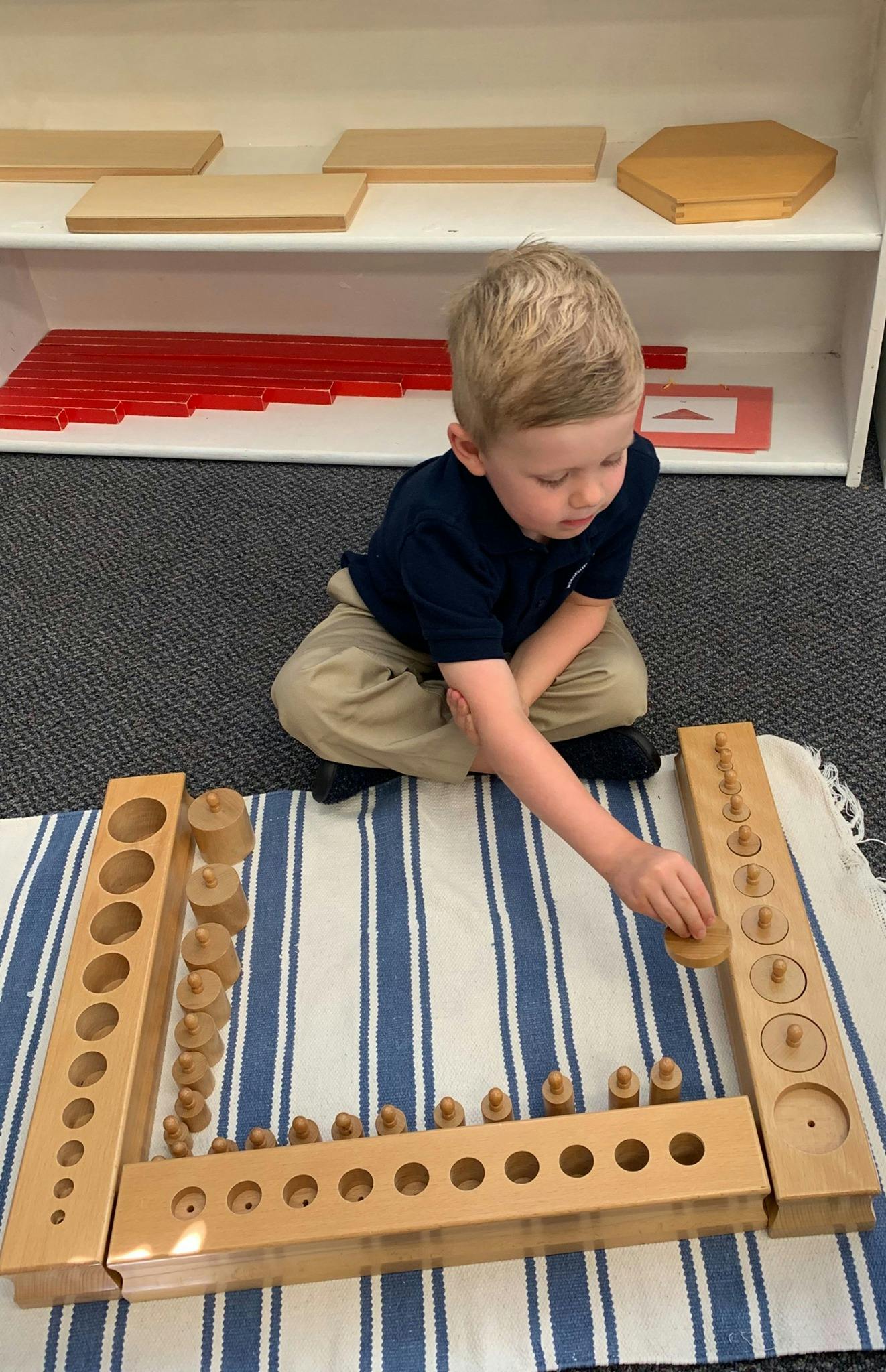 Child playing with wooden cylinder blocks on a striped mat