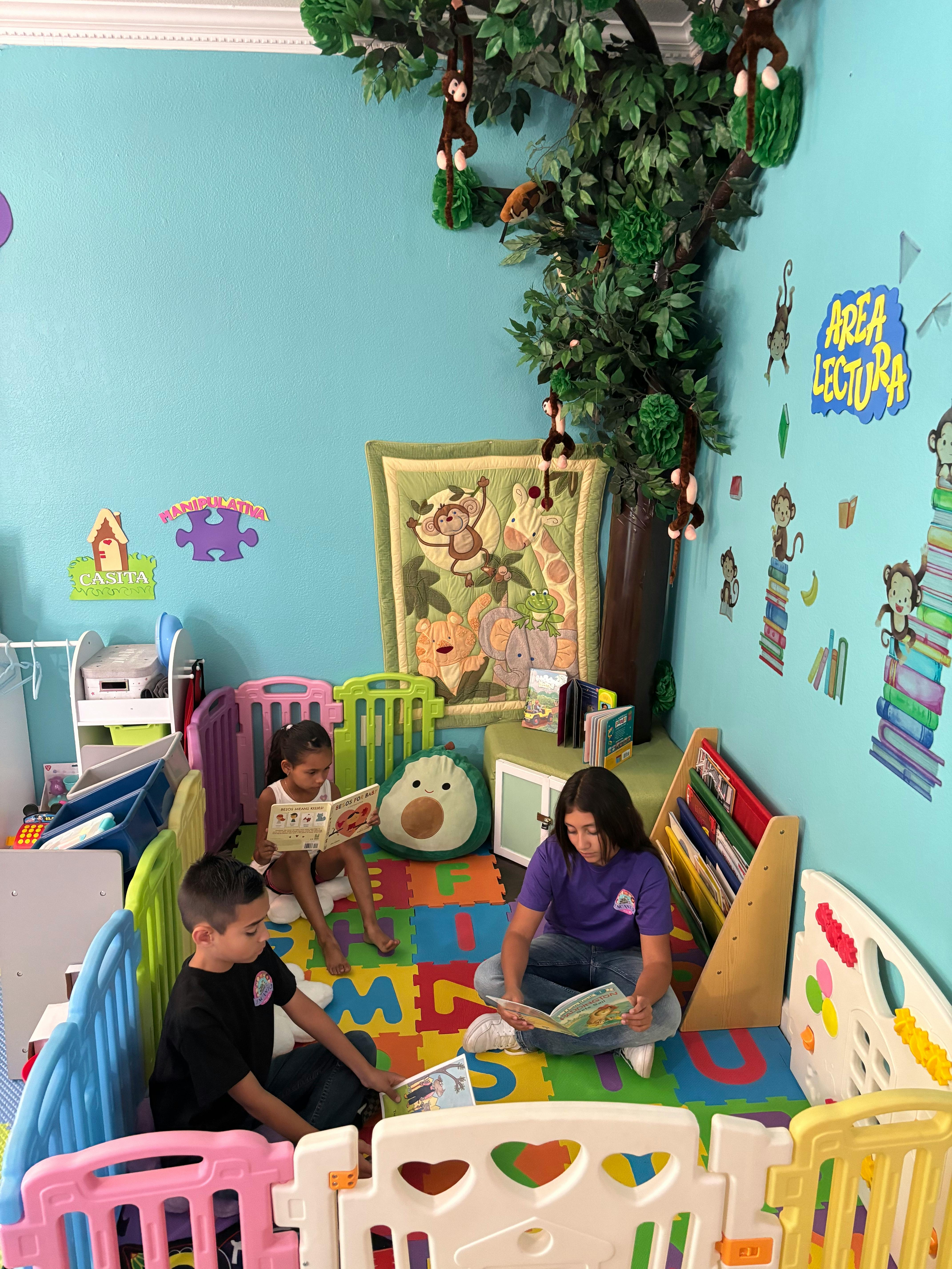 Three people reading books in a play area with colorful floor mats