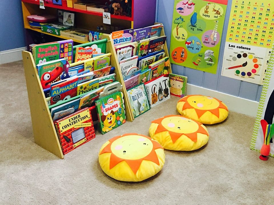 Children's books displayed on shelves with sun-shaped floor cushions