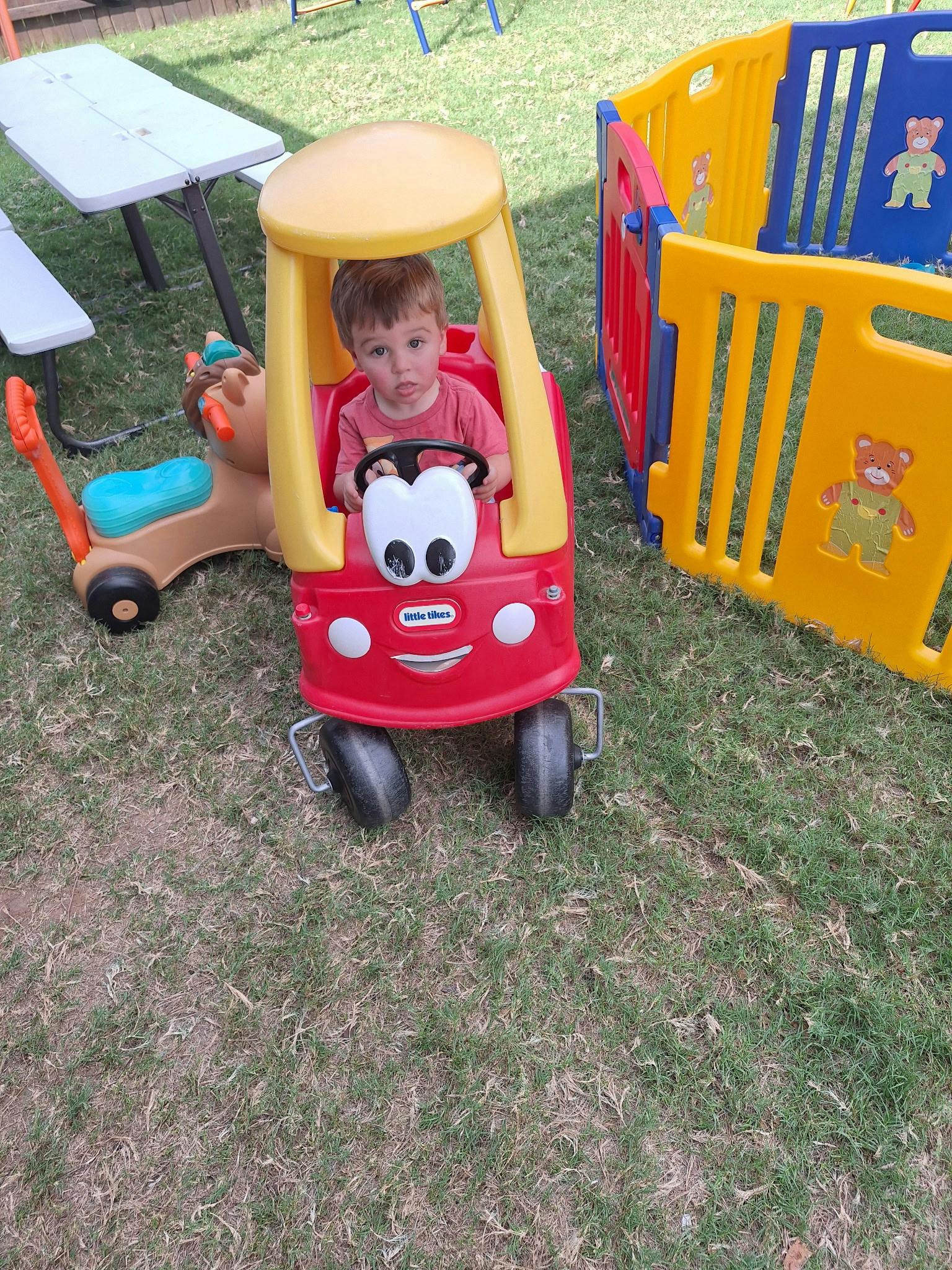 Child in a red and yellow toy car