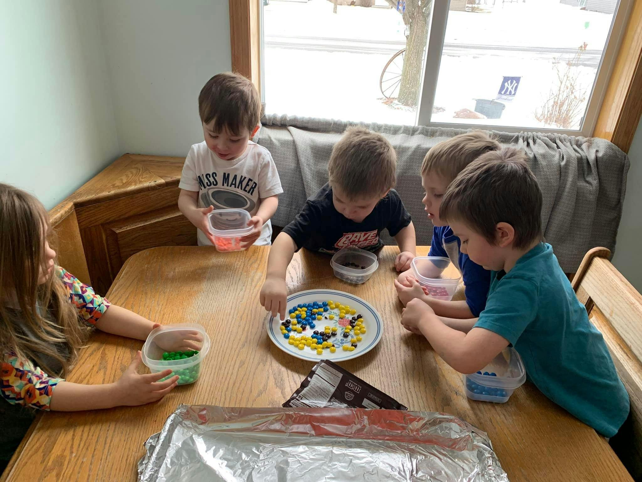 Children at a table decorating with small candies