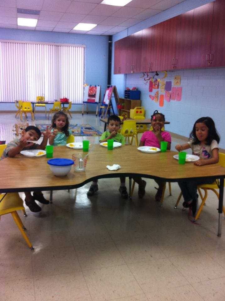 Four children sitting at a table with plates and cups