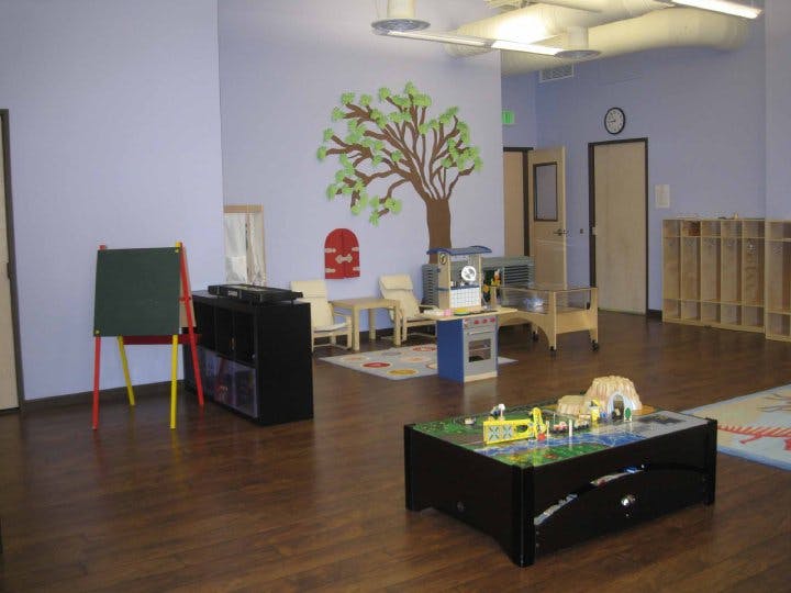 Empty classroom with a tree mural on the wall and various play furniture