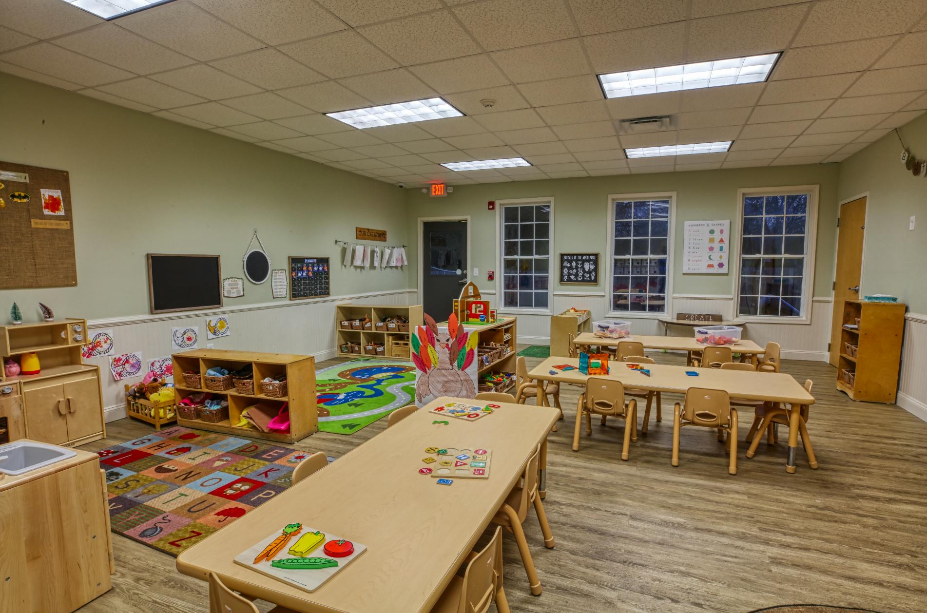 An empty early childhood classroom with multiple small tables and chairs