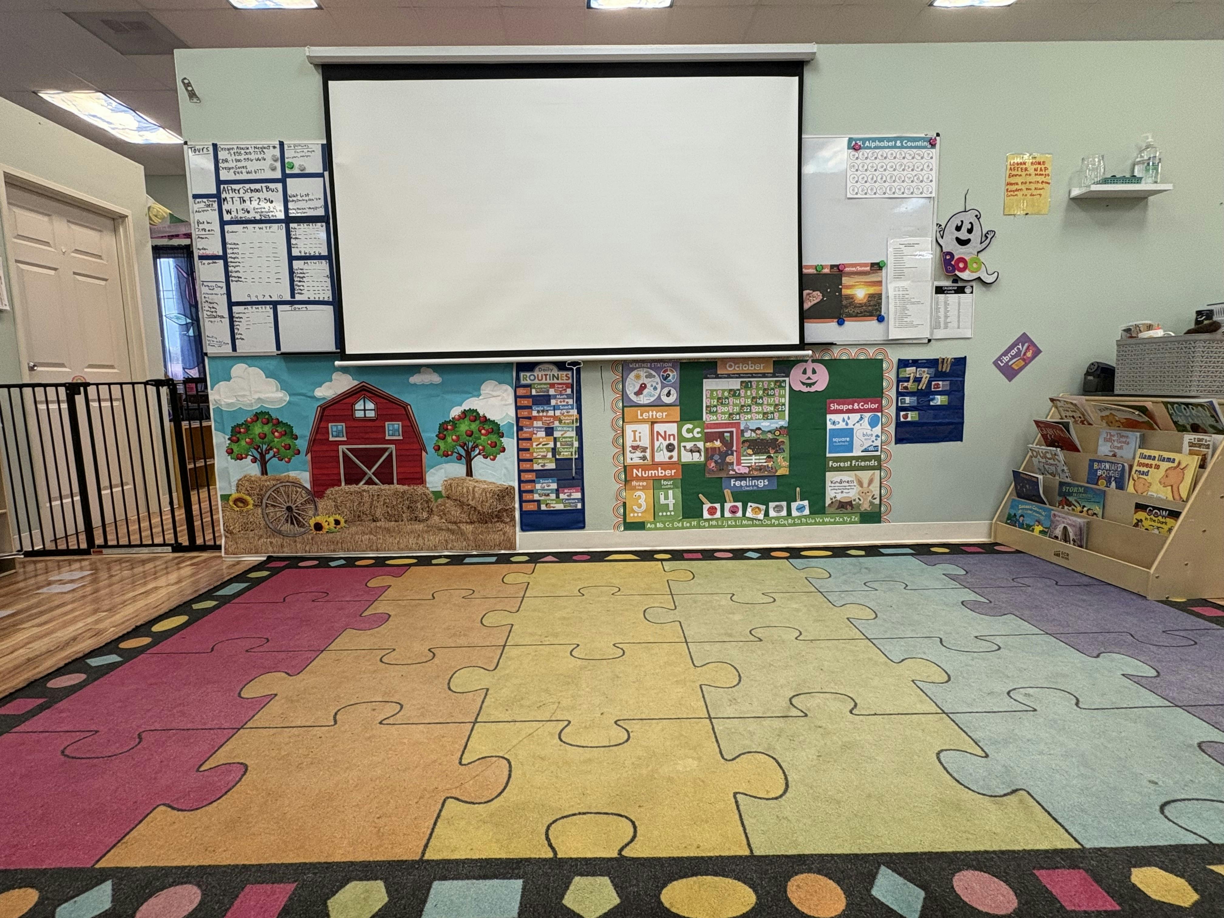 Classroom with a puzzle piece rug and a projector screen