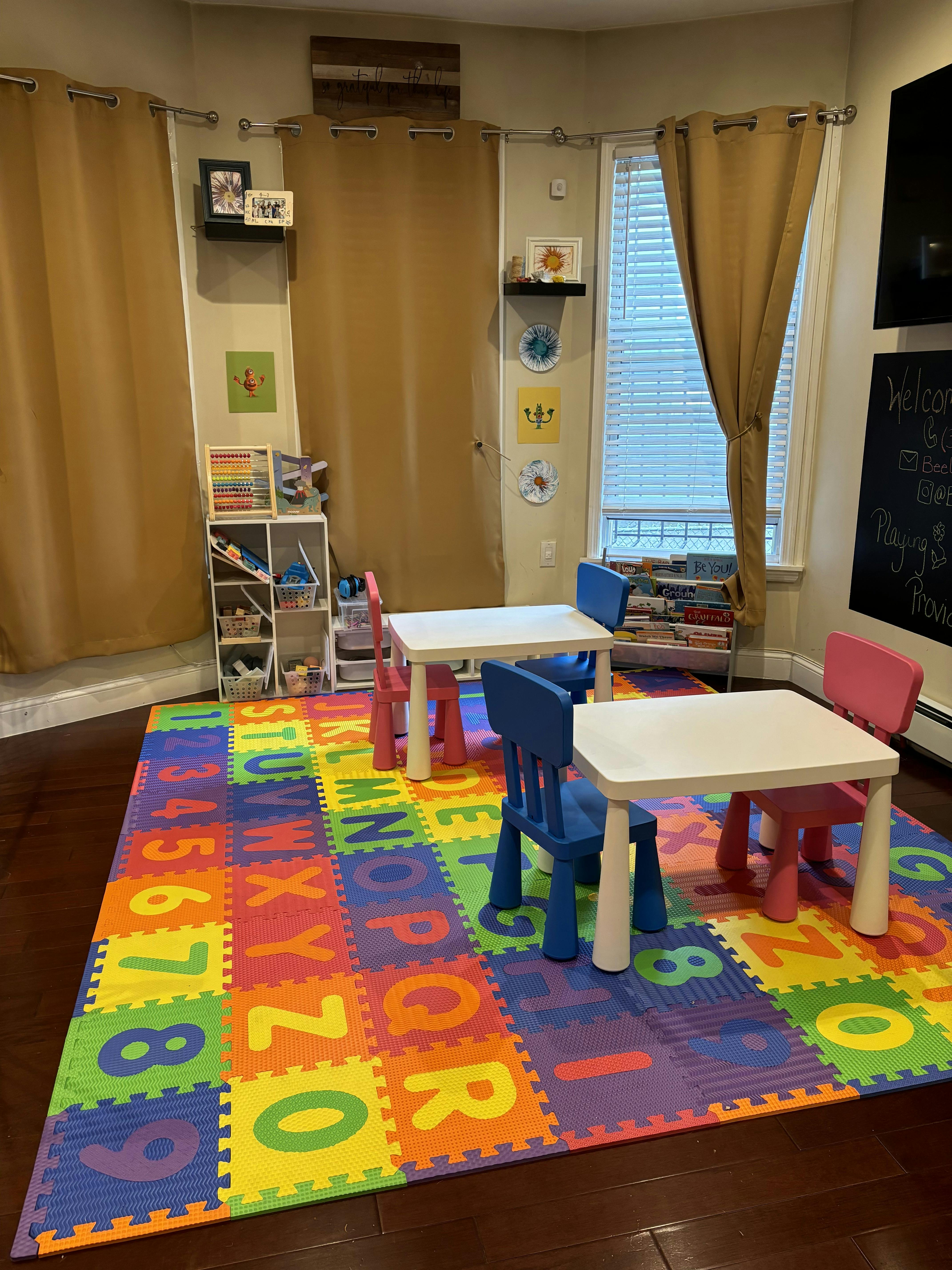 Playroom with colorful alphabet and number mat, small tables, and chairs