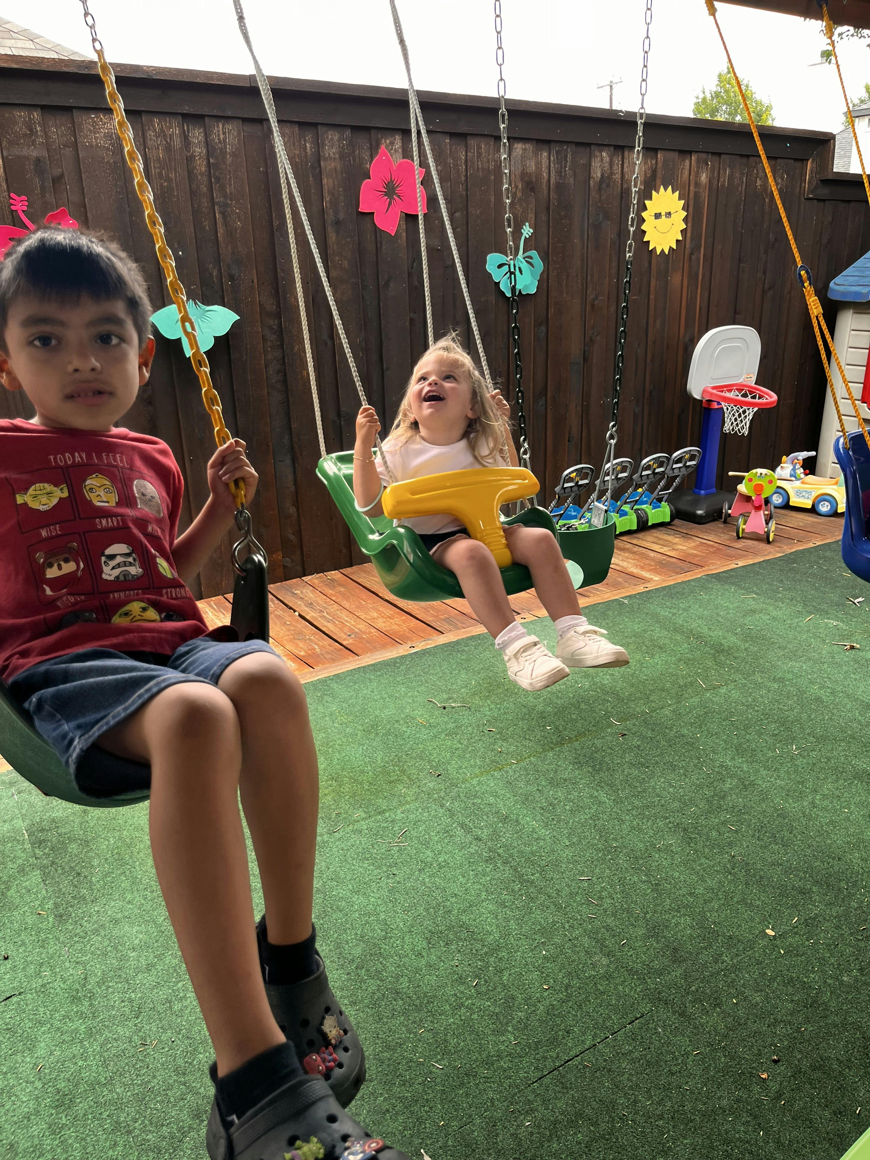 Child and toddler on swings in a backyard playground