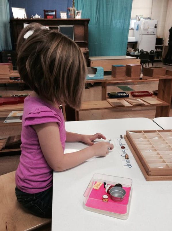 Child sitting at a table, manipulating small objects