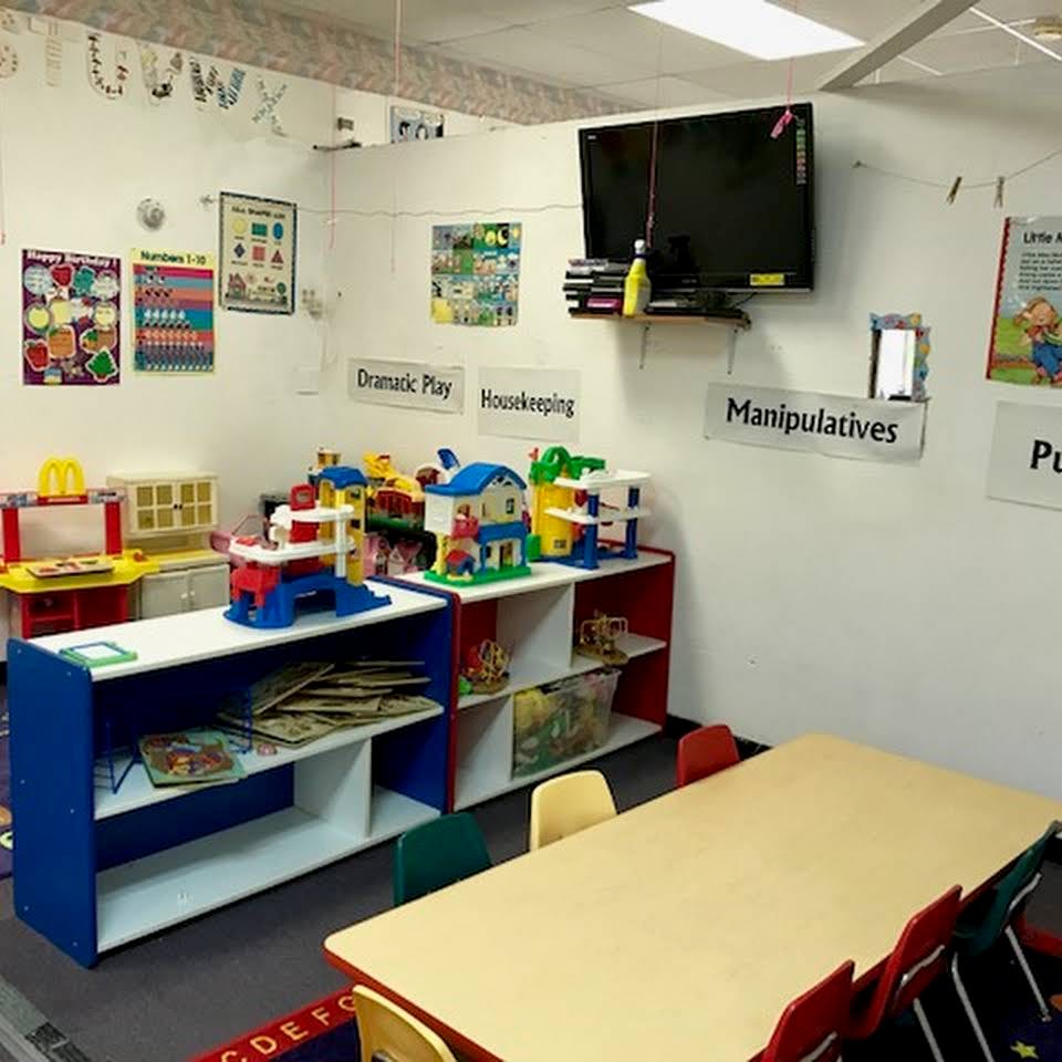 Classroom with toys, shelves, and a long table with chairs