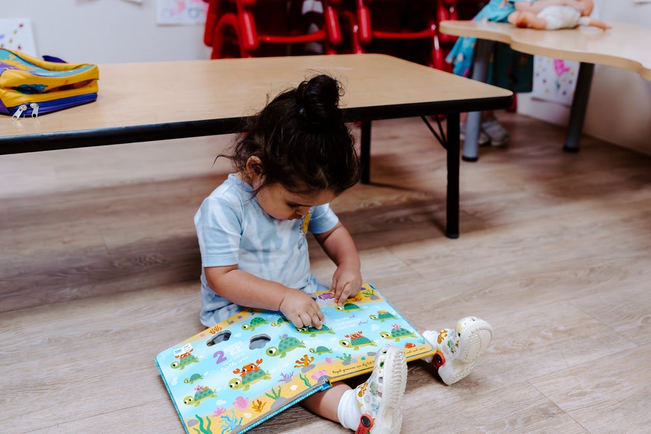 Child sitting on floor looking at an open book