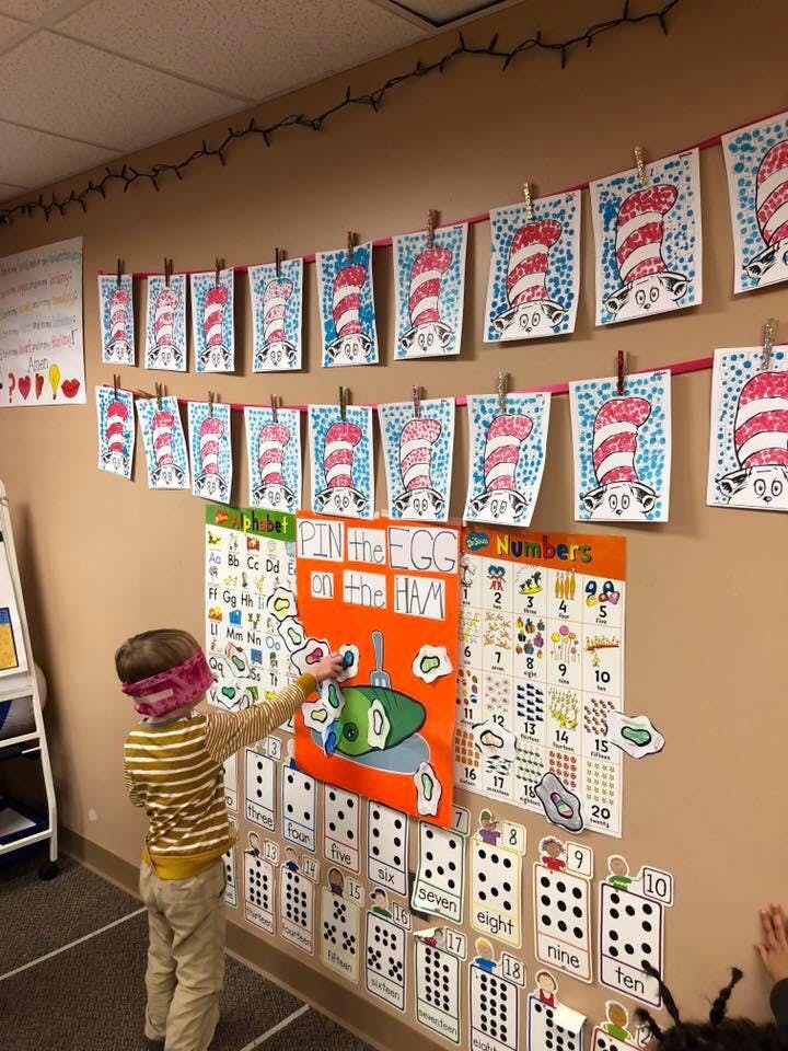 Child blindfolded playing Pin the Egg on the Ham in a classroom