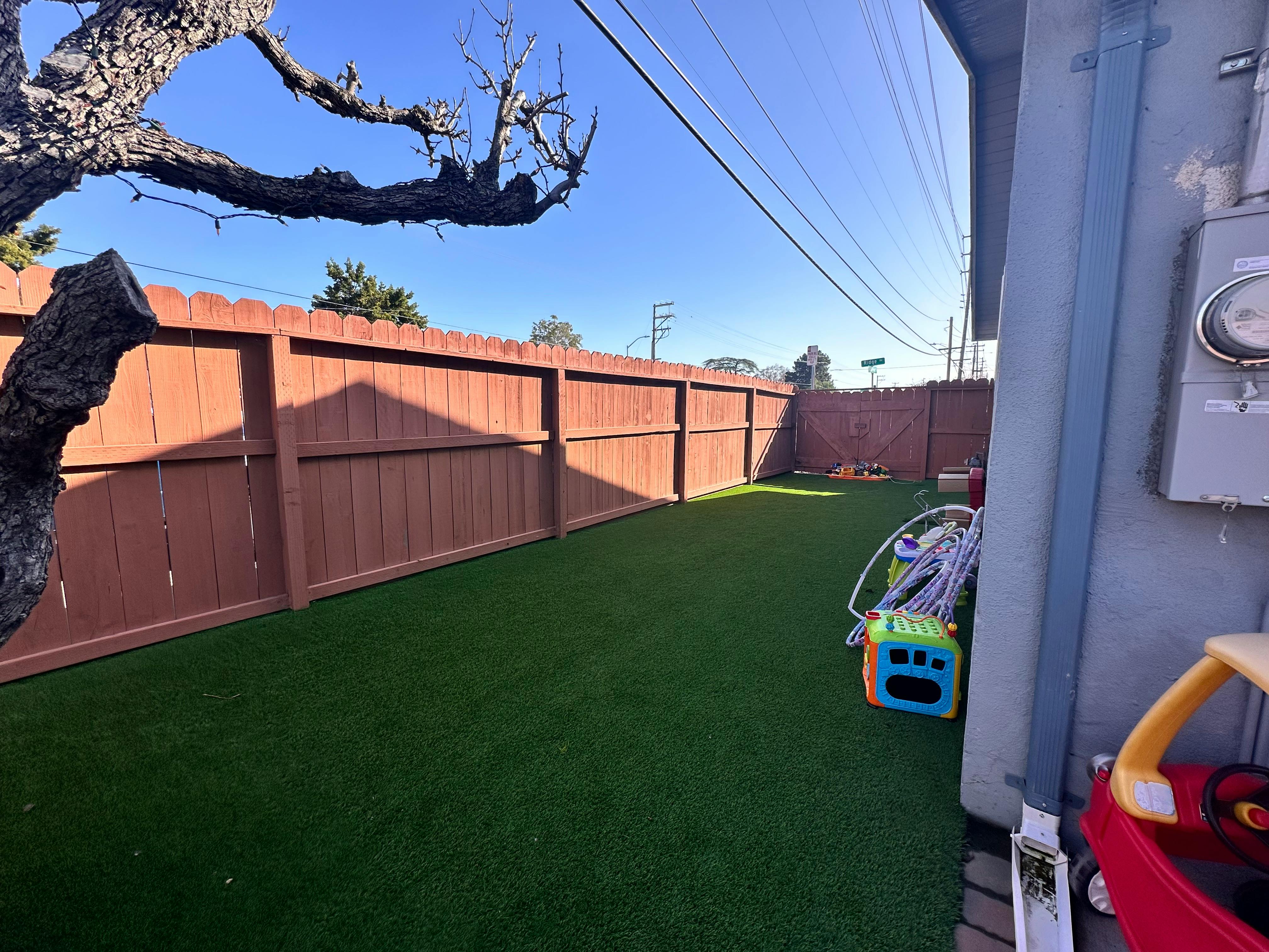 Backyard with artificial turf and a wooden fence
