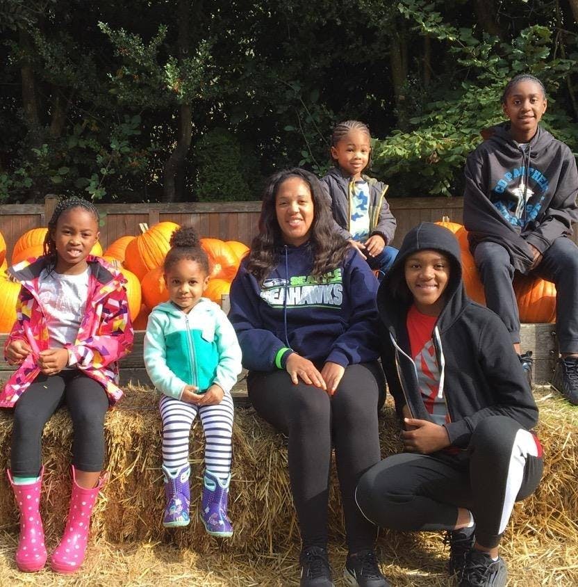 Group of people and children sitting on hay bales with pumpkins