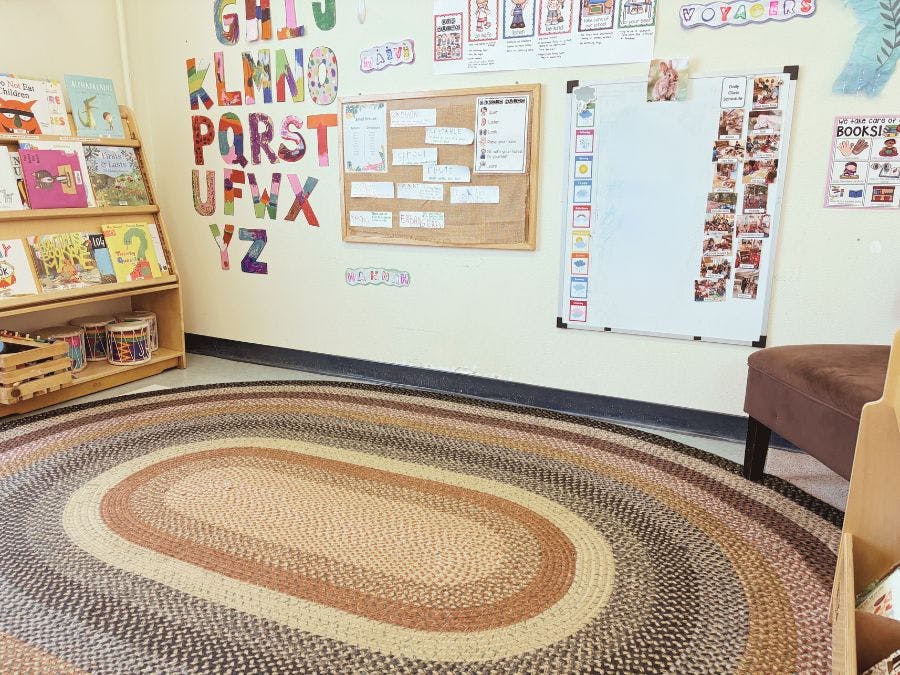 Classroom with alphabet letters on wall, bookshelf, and oval rug