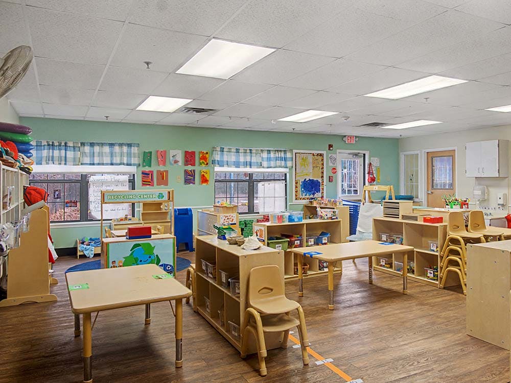 A colorful empty classroom with small tables, chairs, and learning materials