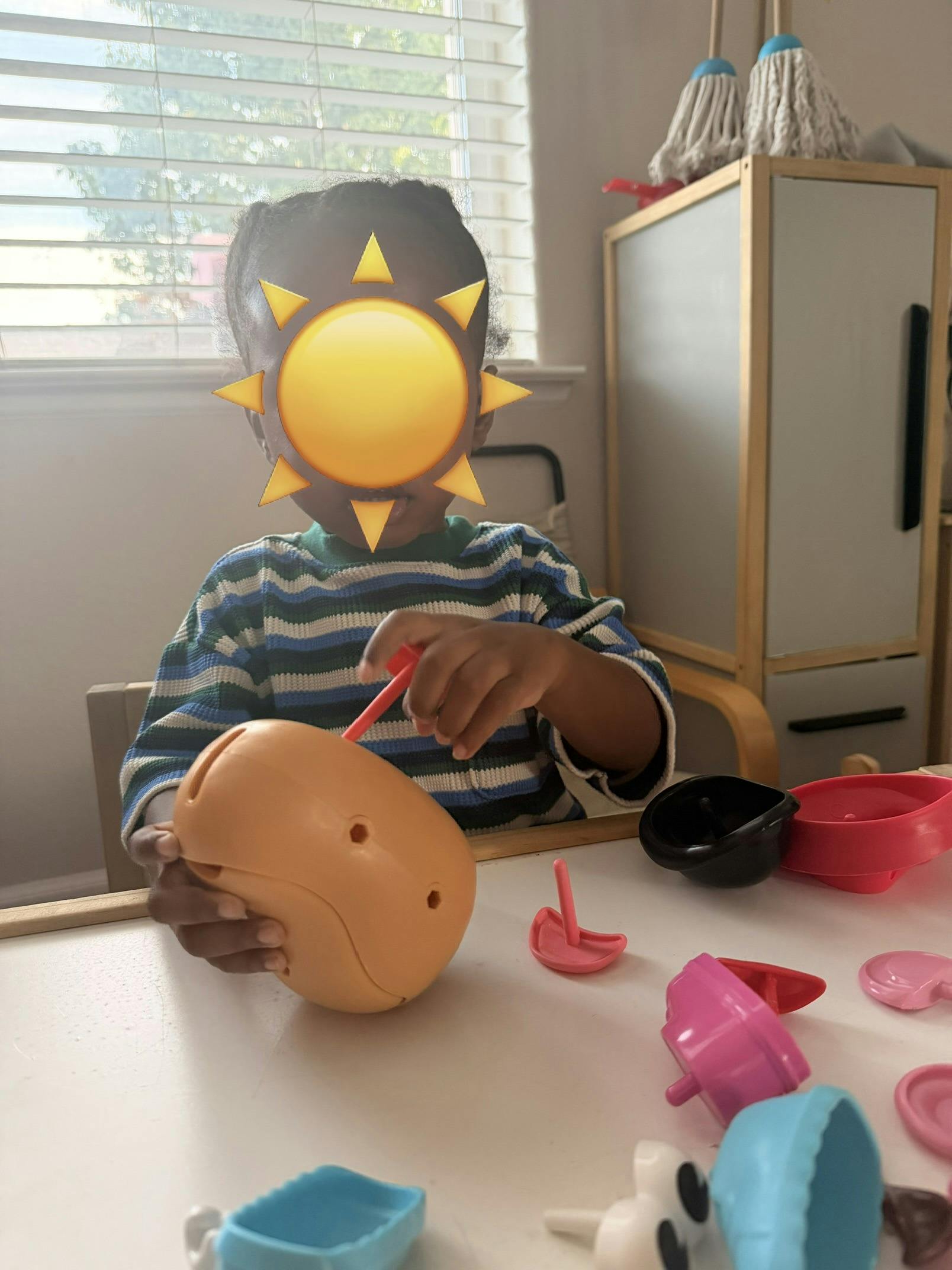 Child playing with a potato-shaped toy at a table