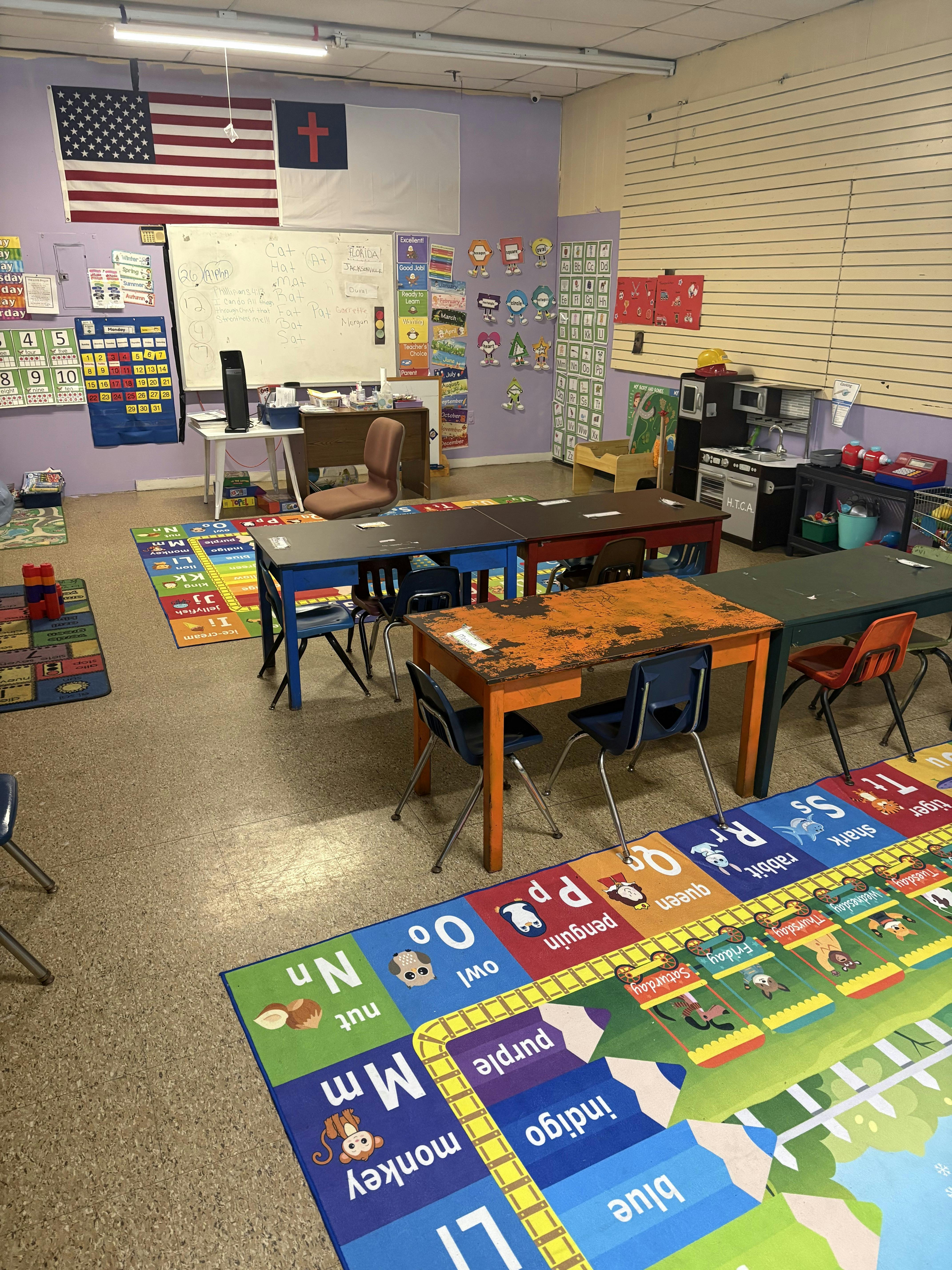 Empty classroom with small desks and educational floor rugs