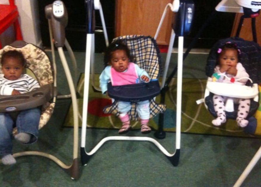 Three children sitting in baby swings and high chairs