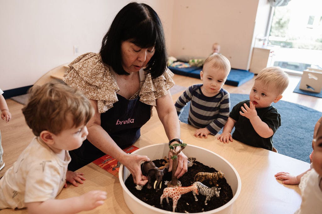 Adult and children playing with animal figures in a sensory bin