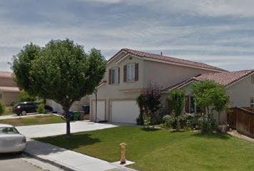 Two-story house with a tree in the front yard