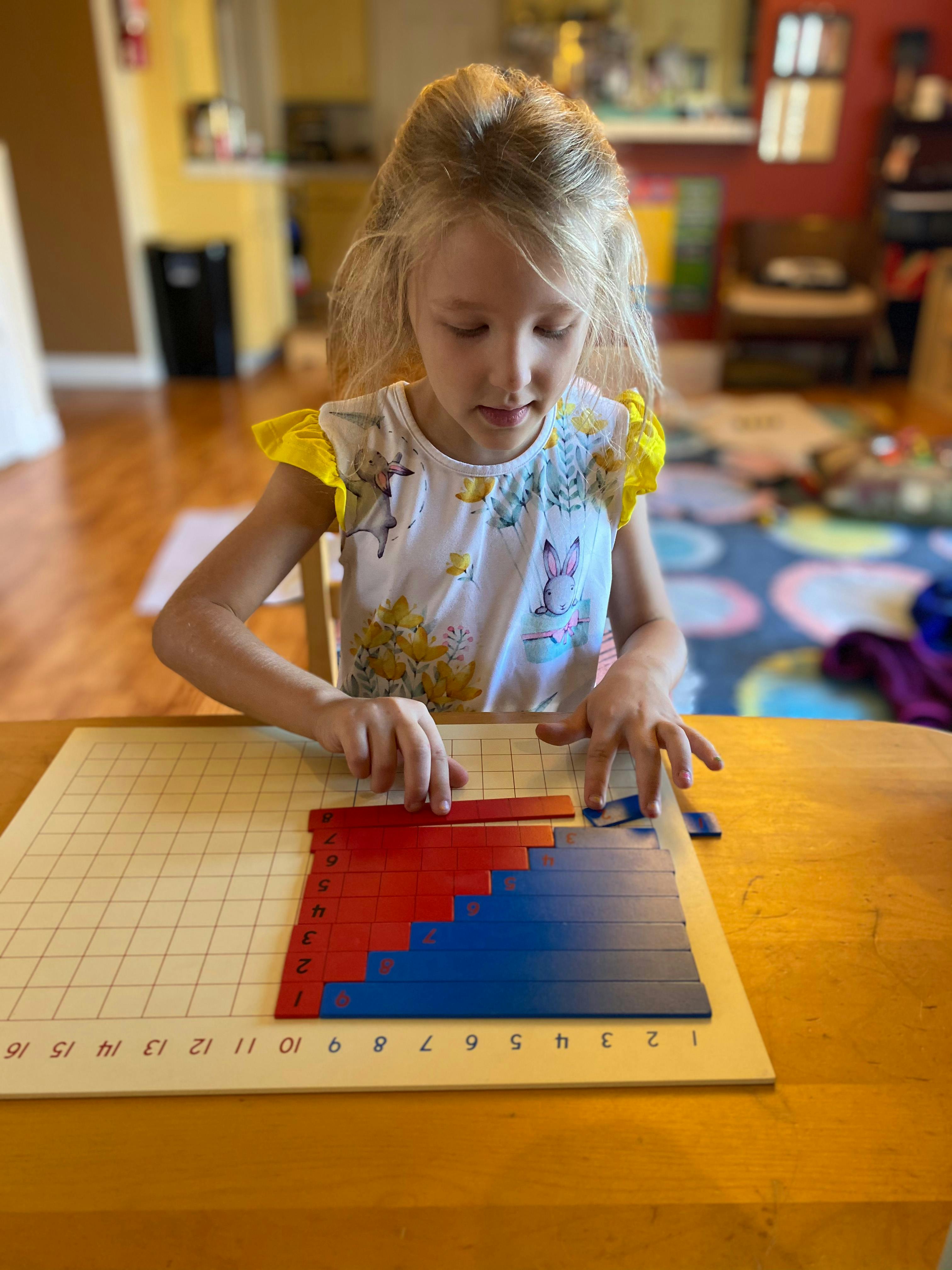 Child arranging red and blue blocks on a numbered grid