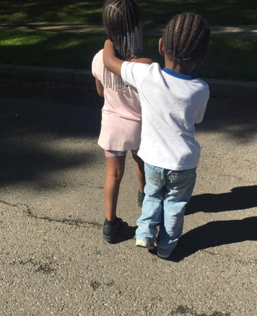 Two children standing with one child's arm around the other