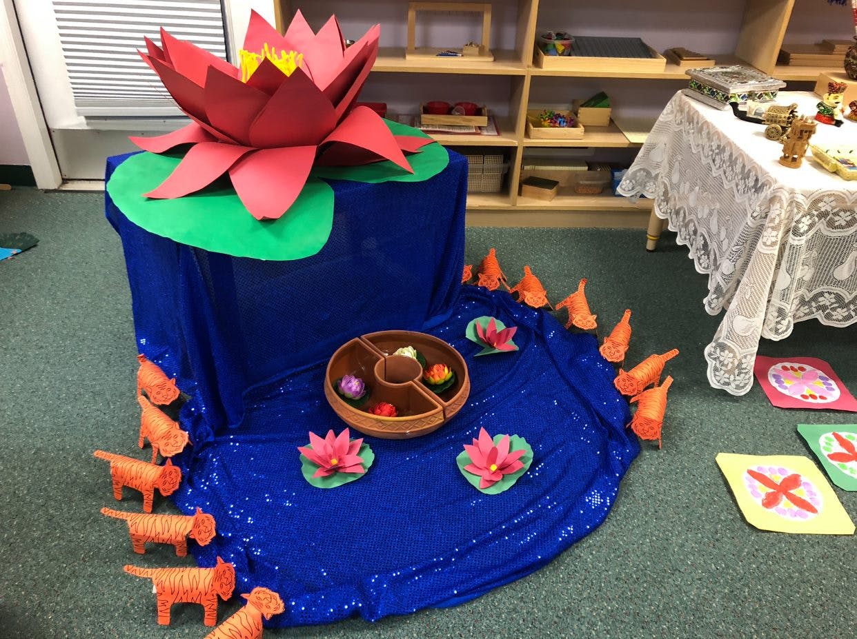 Paper lotus flower display with blue fabric pond and orange animal cutouts