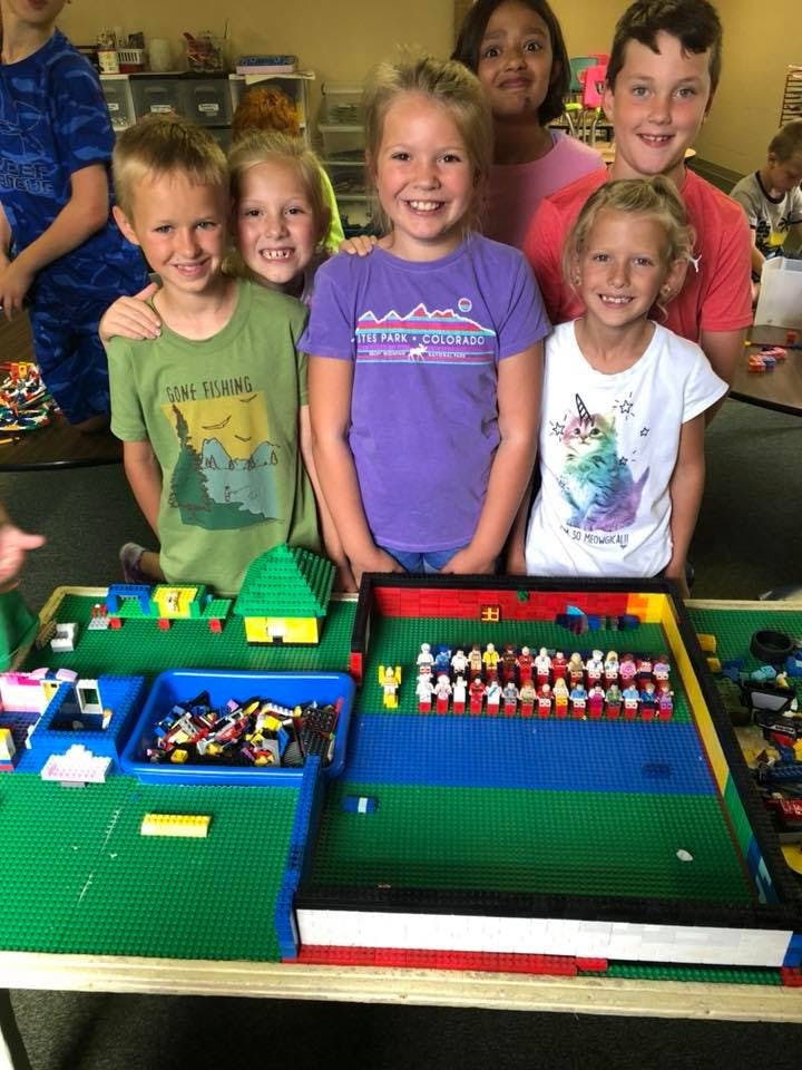 Group of children standing behind a table with Lego creations