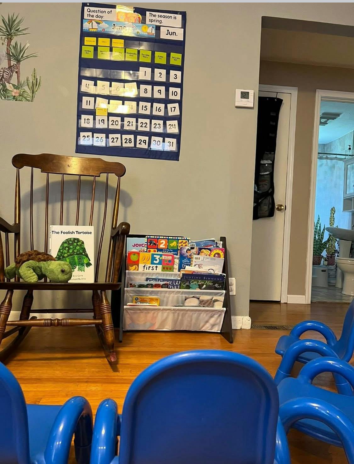 Calendar on wall above rocking chair and book display