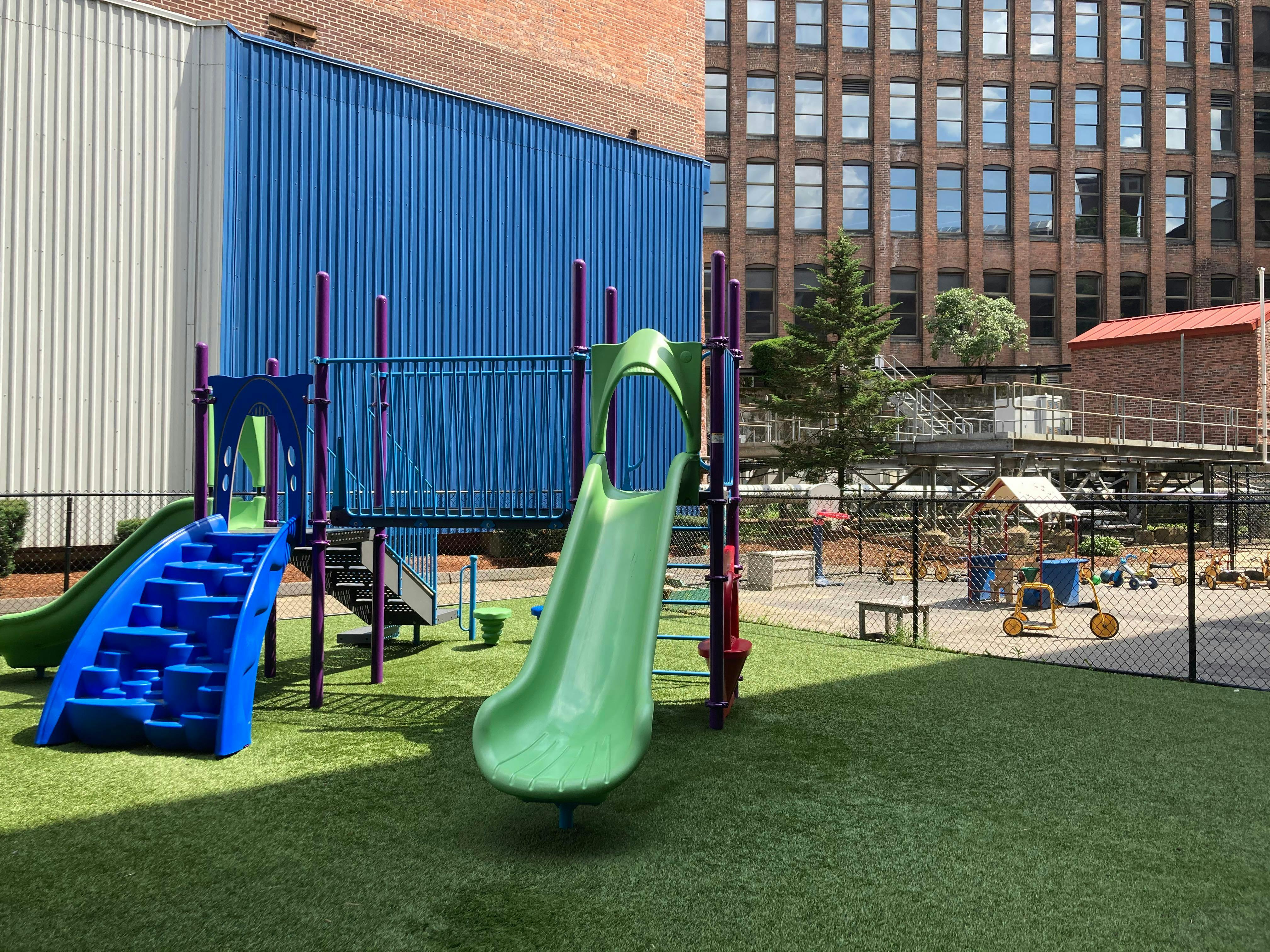 A colorful playground with slides and a climbing structure on artificial turf