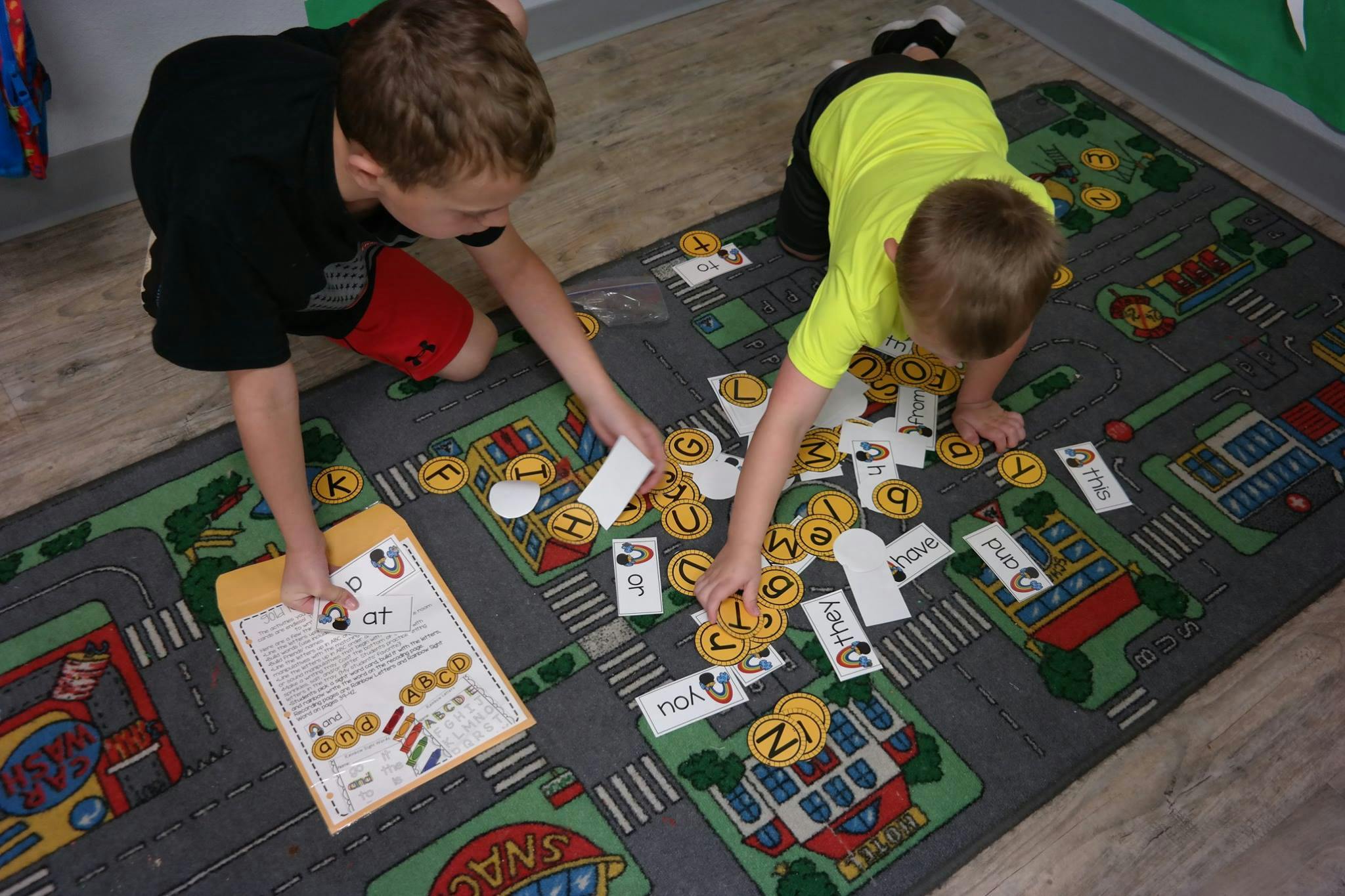 Two children playing with letter tiles on a rug