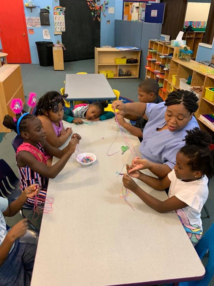 Adult and children making crafts at a table in a classroom