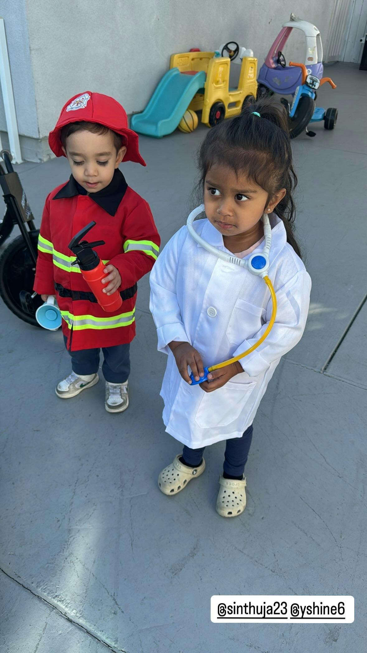 Two children in costumes, one as a firefighter and one as a doctor