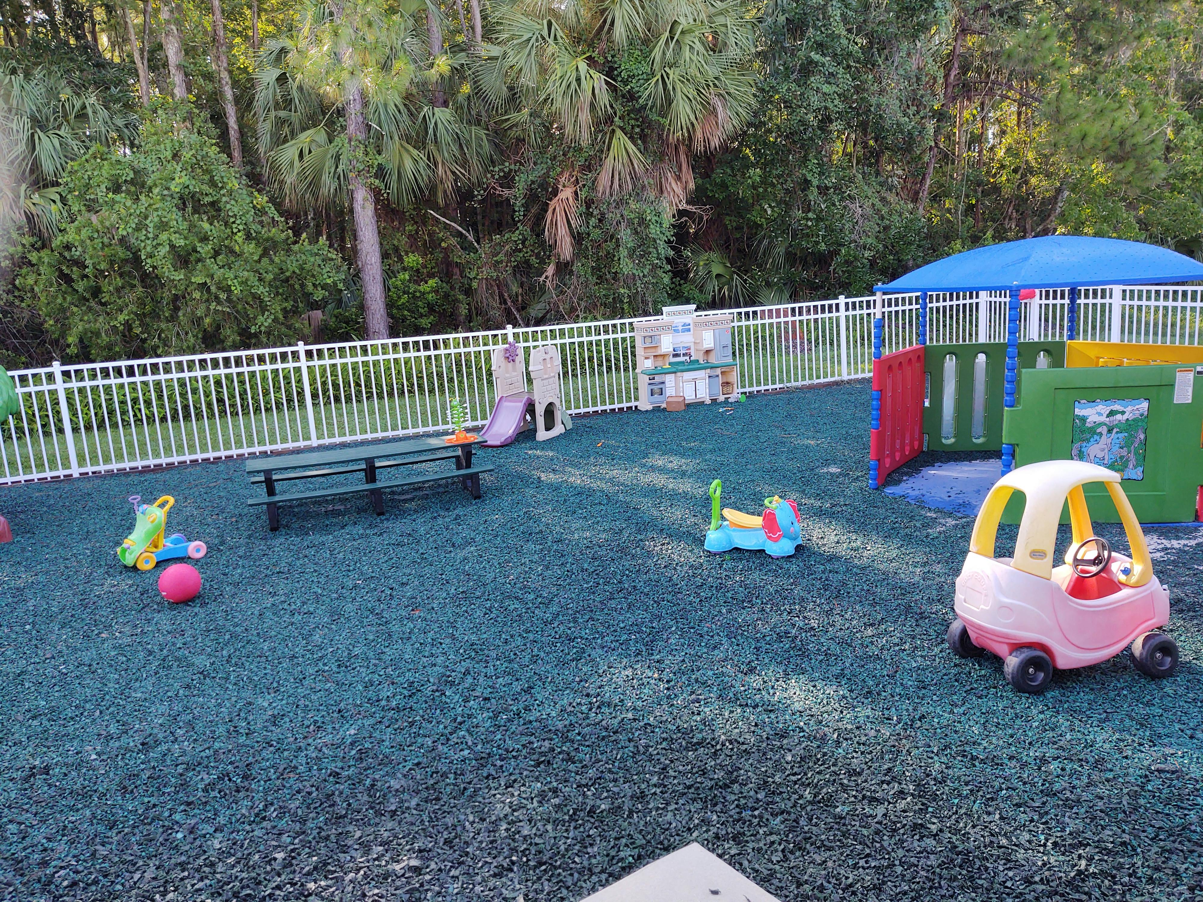 Playground area with various toys and play equipment on rubberized surface