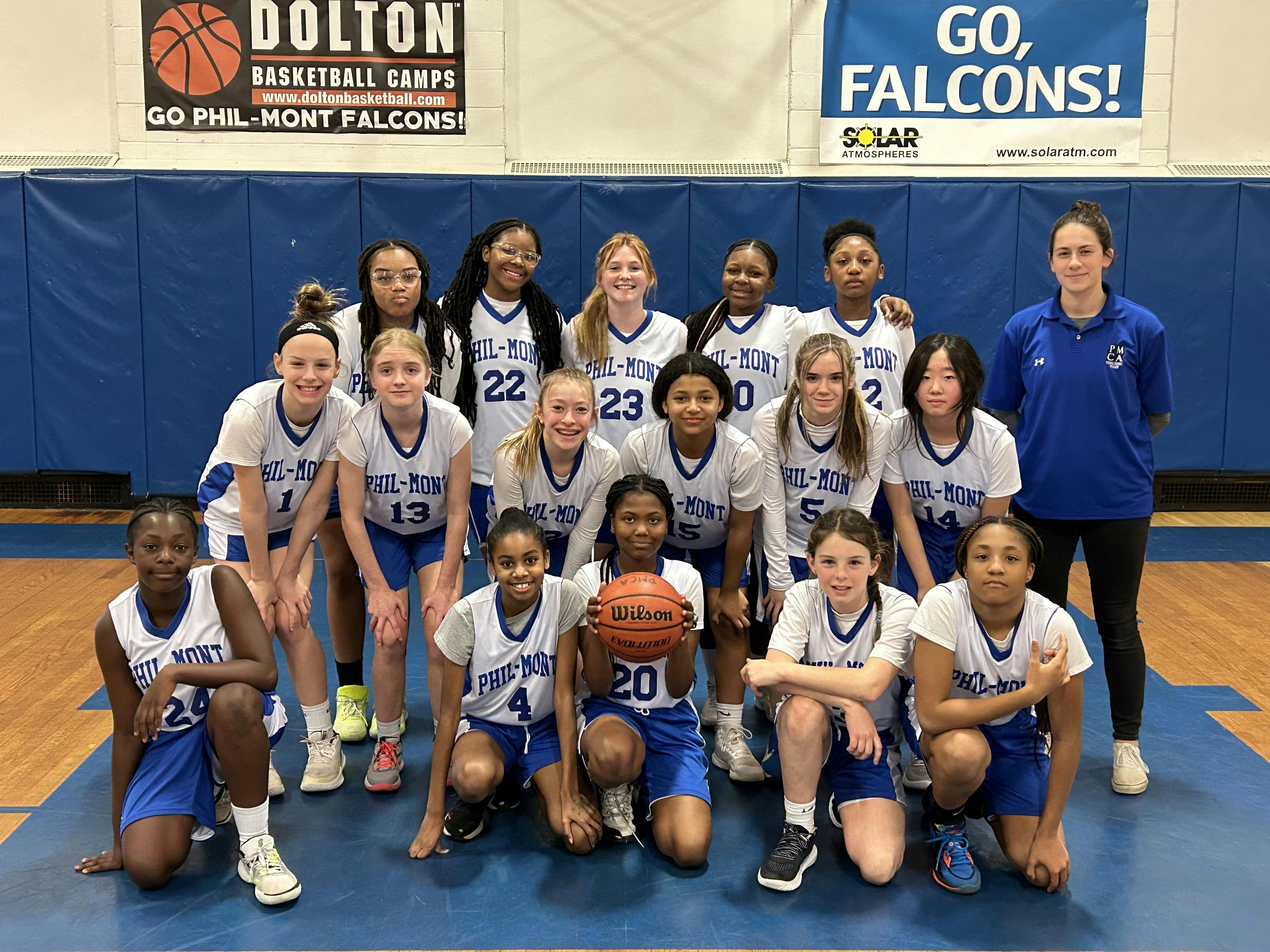 Group of teens and adults in basketball uniforms posing on a court