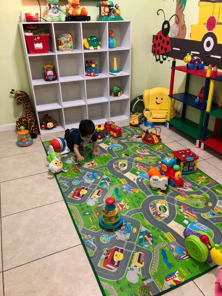 Child crawling on a playmat with toy cars and buildings