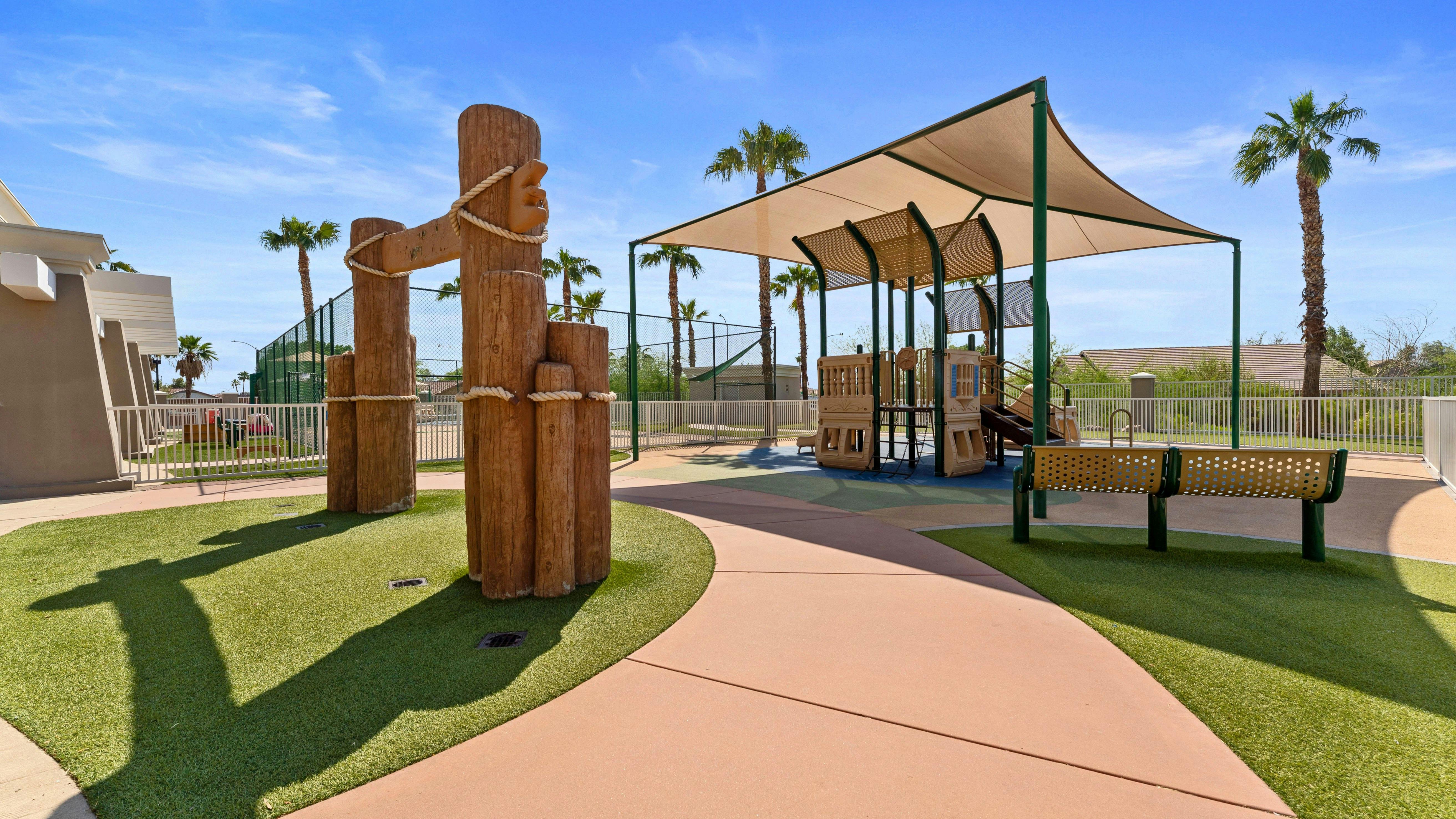 Outdoor playground with palm trees and shade covering