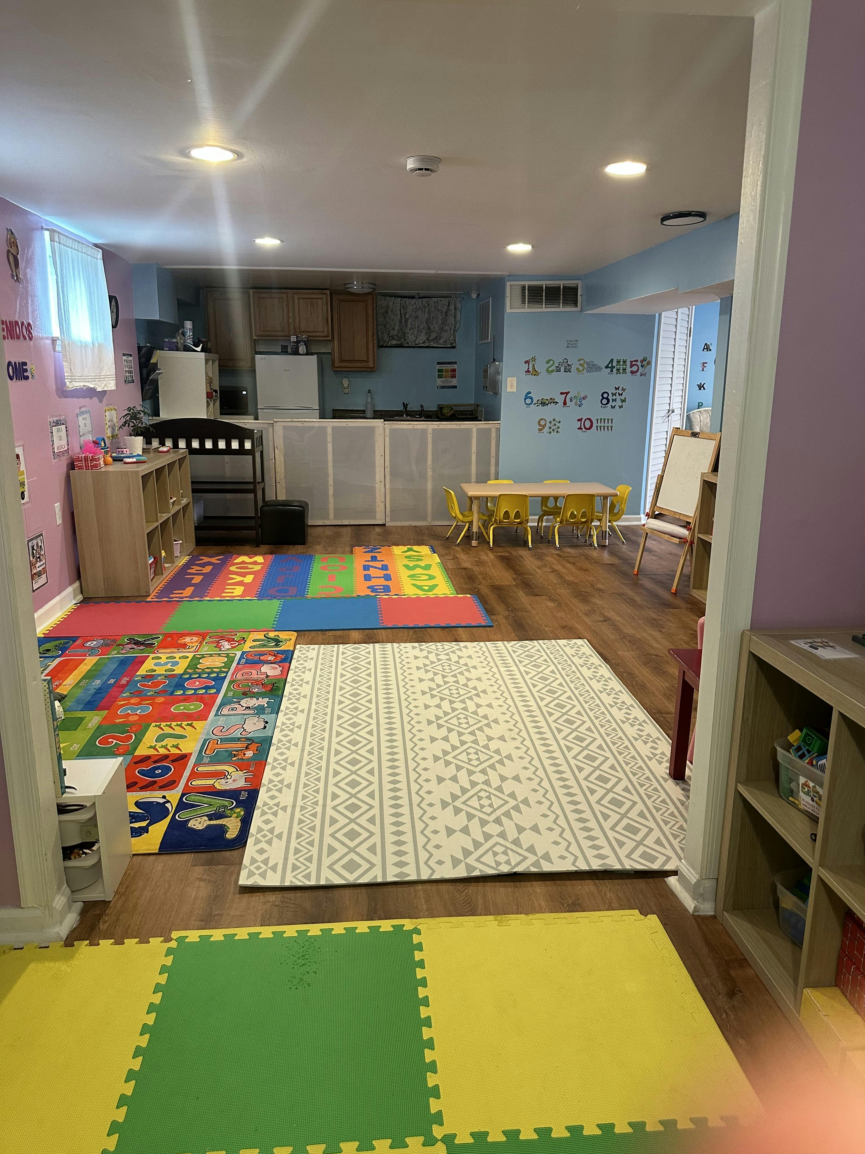 Playroom with colorful rugs, small table and chairs, and a kitchen area