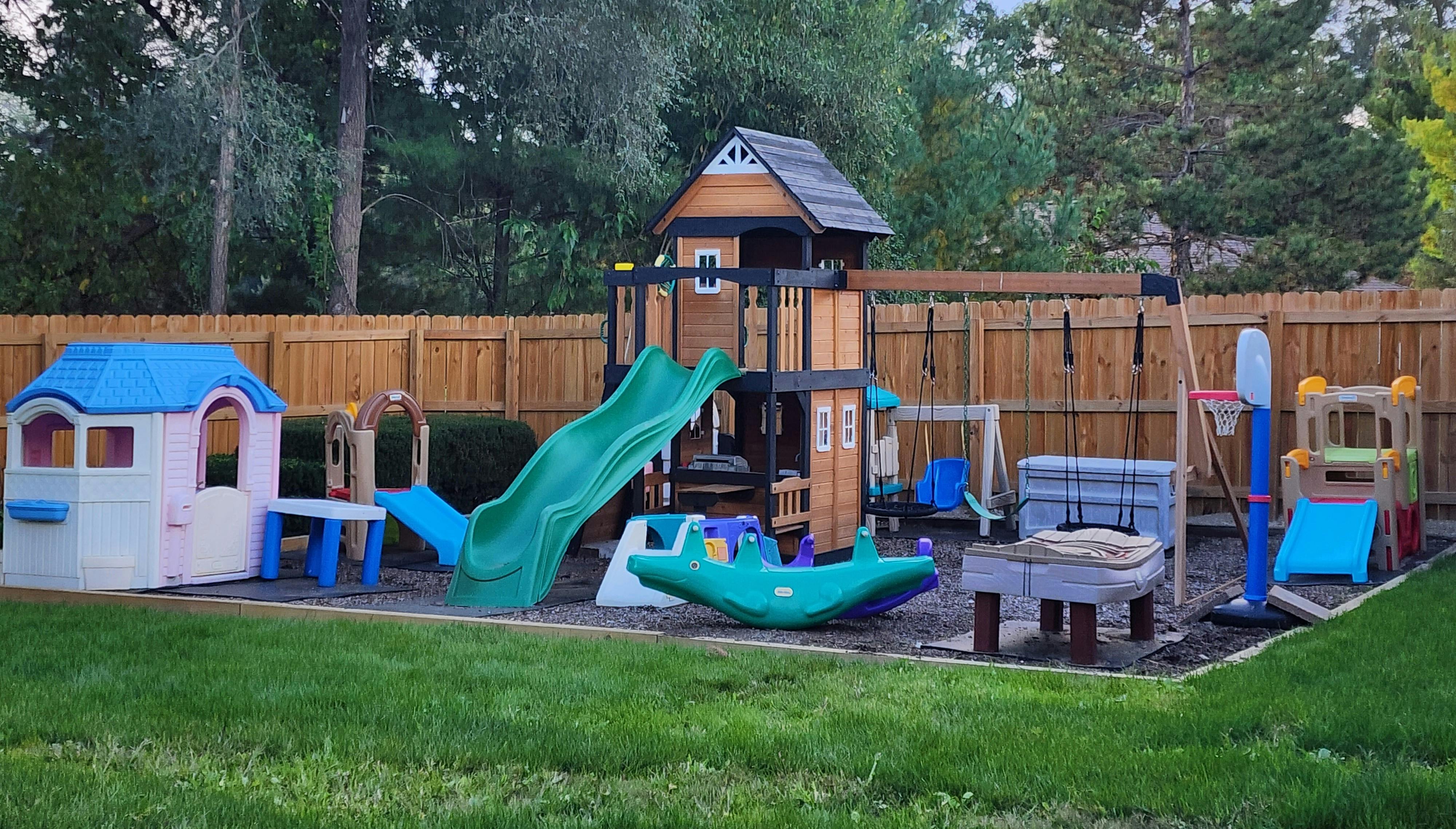 Outdoor playground with playhouse, slide, swings, and basketball hoop