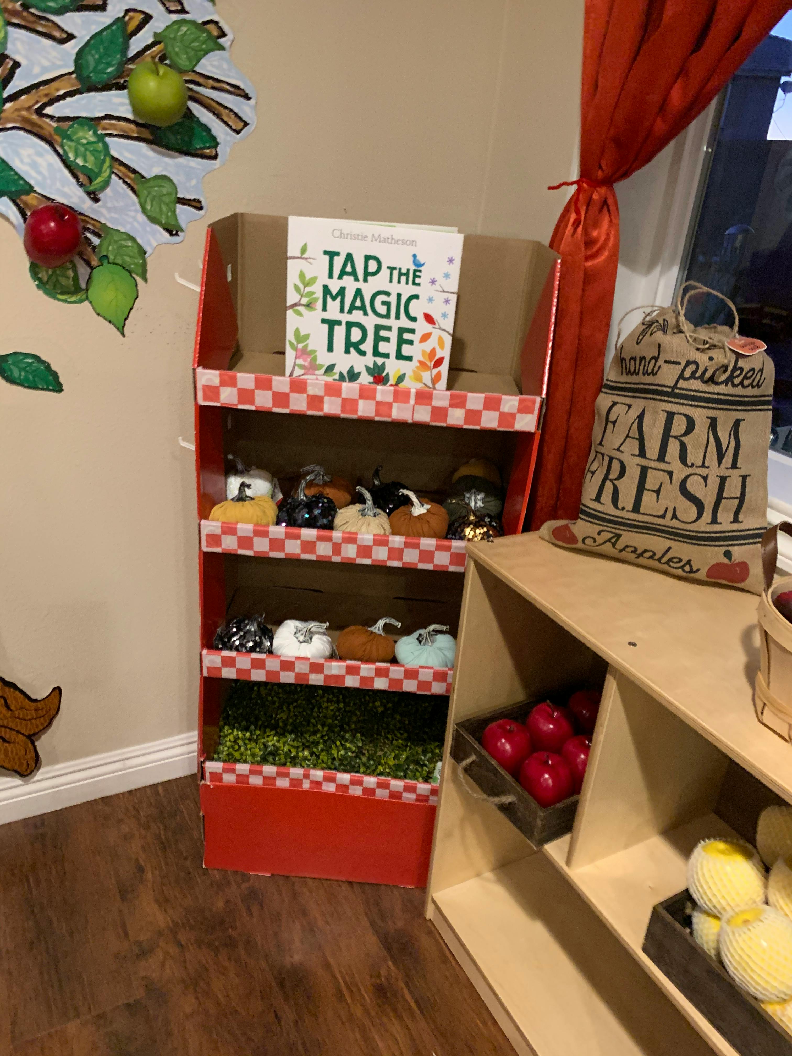 Display with "Tap the Magic Tree" book, decorative pumpkins, and apples