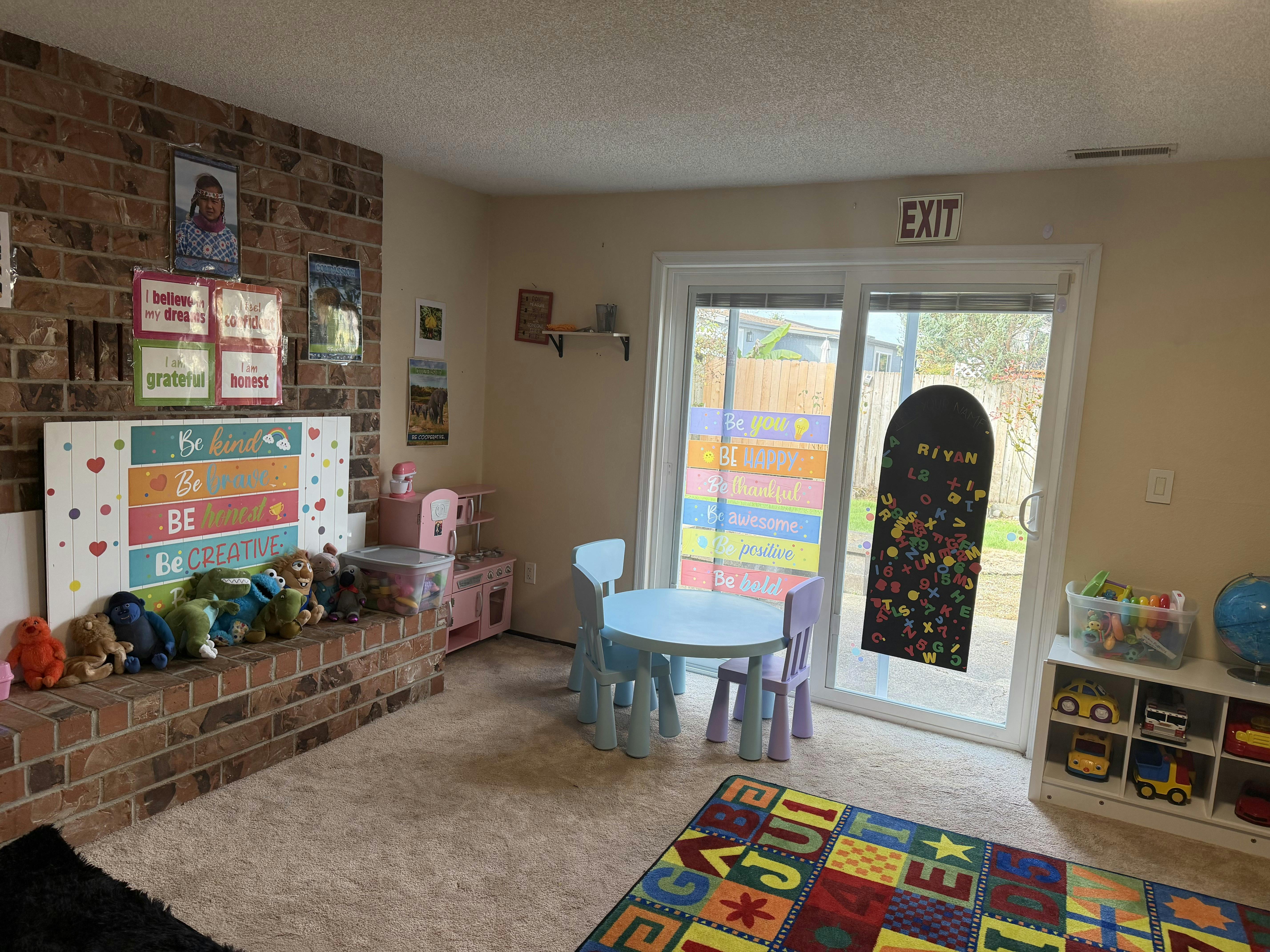 Colorful playroom with small chairs, a round table, and a brick fireplace