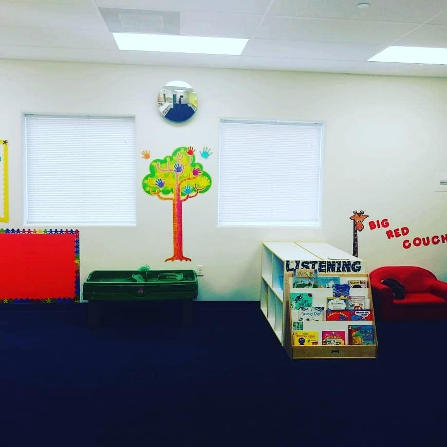 Children's room with tree decal, book display, and red couch