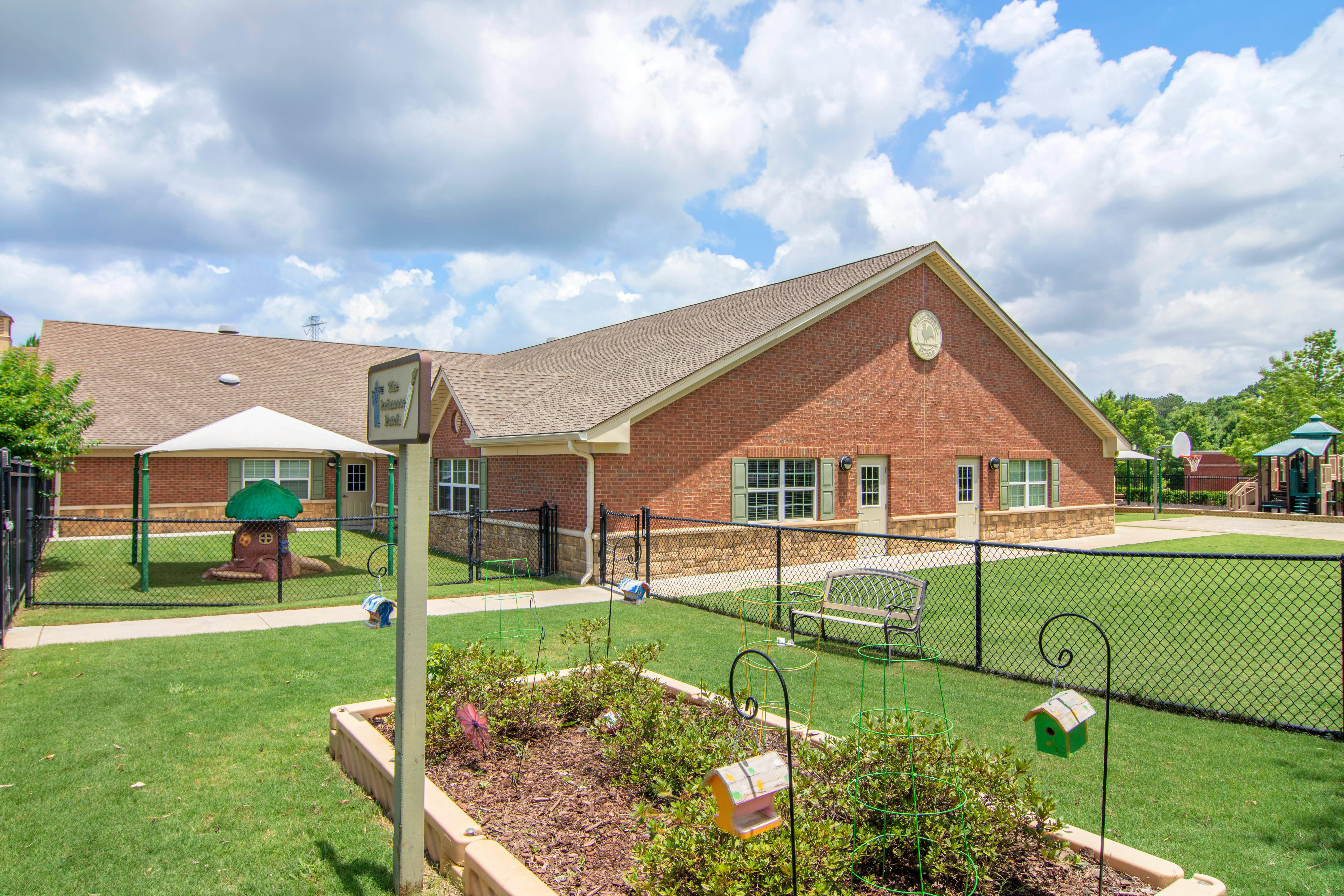 Brick building with fenced yard and playground on a sunny day
