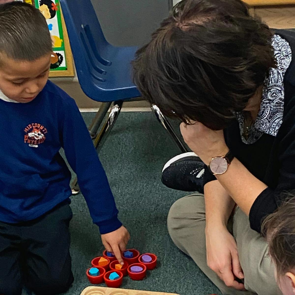 Child and person on floor playing with colorful sorting toy