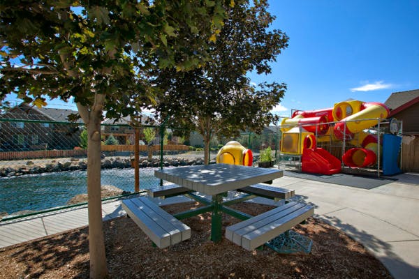 Picnic table and playground equipment next to a body of water